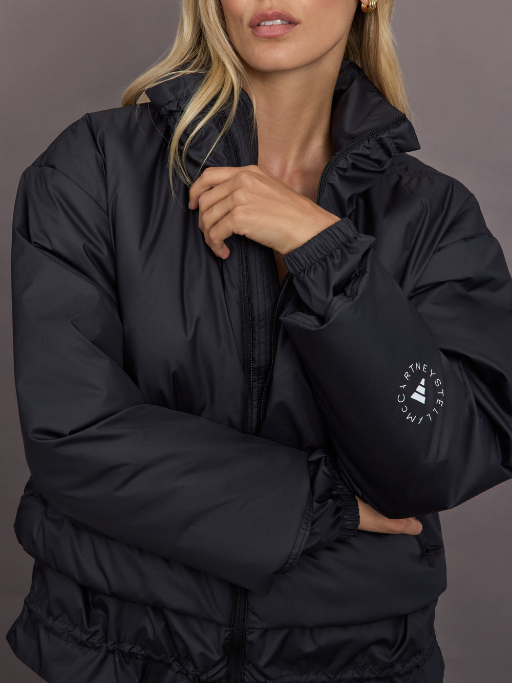 Model is wearing Liner Water-Resistant Jacket in black, close-up zipper and logo detail.