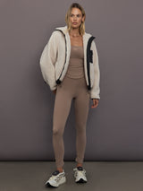 Model is wearing adidas by Stella McCartney Studio Spaghetti Crop Top in Chalky Brown, layered under fleece jacket styling.