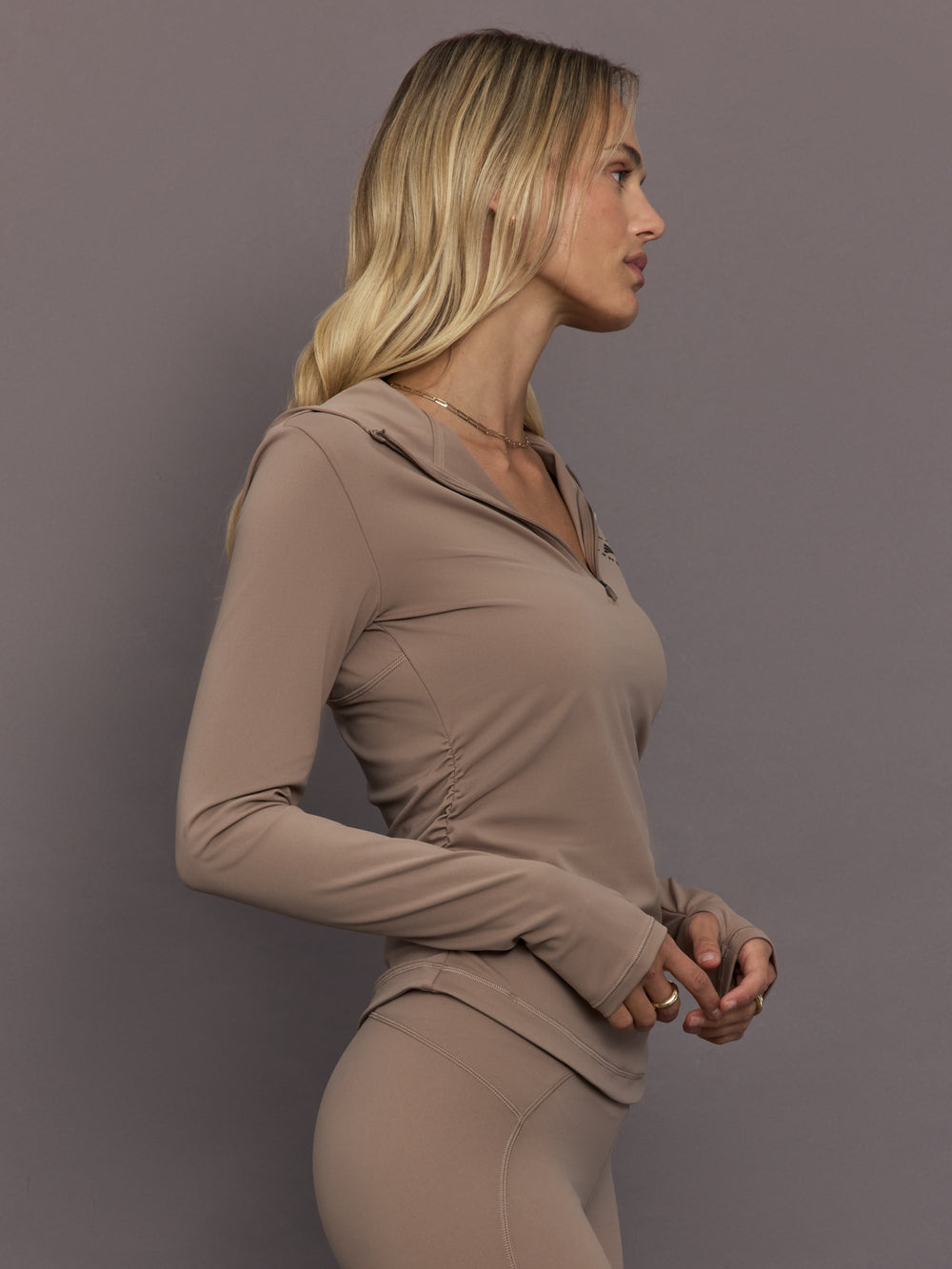 Model is wearing Studio Ruched Half-Zip Top in Chalky Brown, side view.