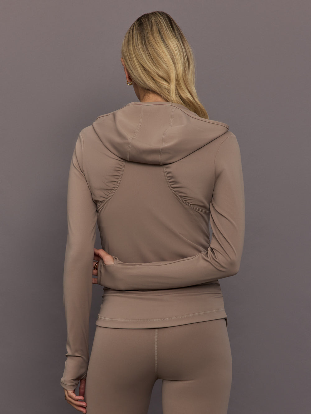Model is wearing Studio Ruched Half-Zip Top in Chalky Brown, back view.