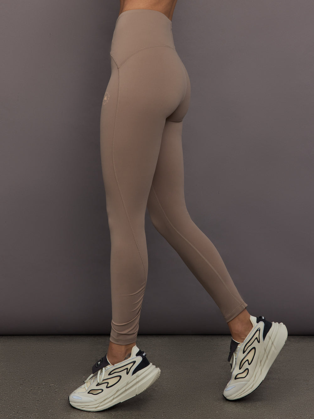 Model is wearing Studio Ruched High-Rise Legging in Chalky Brown, side view.
