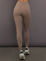 Model is wearing Studio Ruched High-Rise Legging in Chalky Brown, back view.