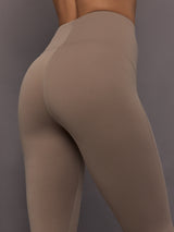 Model is wearing Studio Ruched High-Rise Legging in Chalky Brown, close-up seam detail.