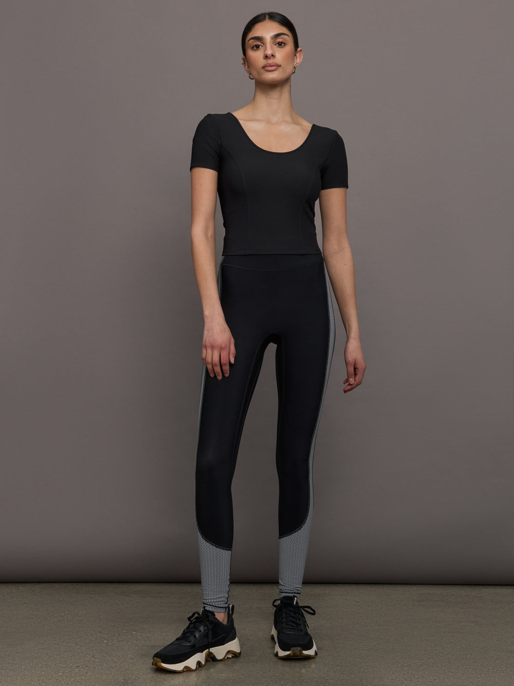 Model wears a cropped black scoopneck short sleeve top.