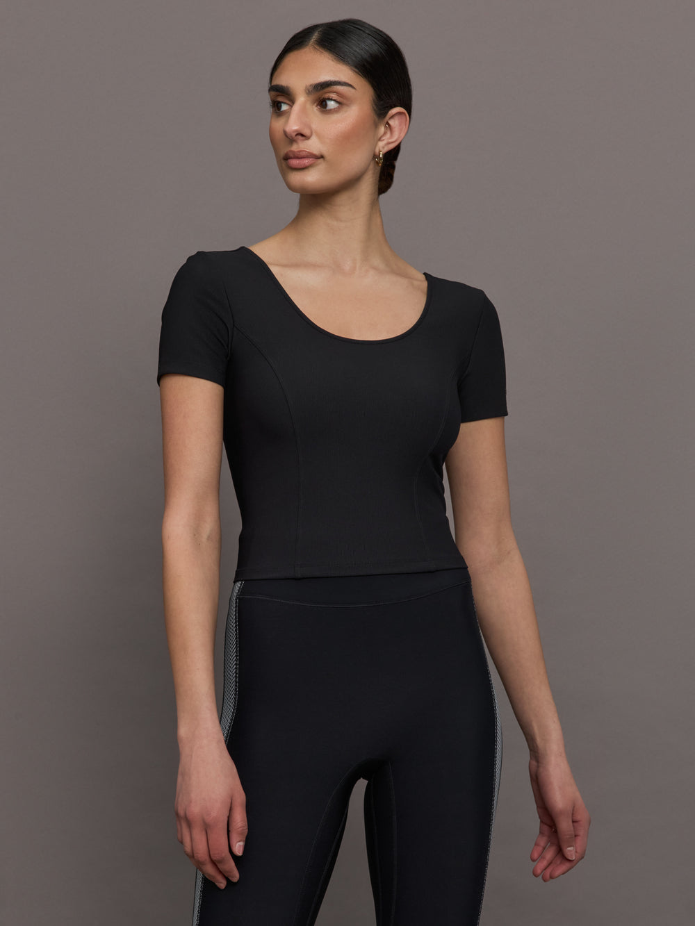 Model wears a cropped black scoopneck short sleeve top.