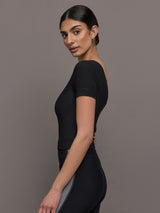 Model wears a cropped black scoopneck short sleeve top.