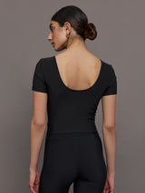 Model wears a cropped black scoopneck short sleeve top.