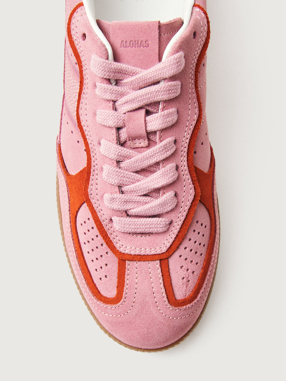 Pink clay colored suede low top lifestyle sneaker with red detailing. 