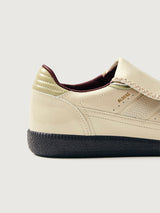 Creme colored low top lifestyle sneaker with black sole & gold/creme heel detailing. 