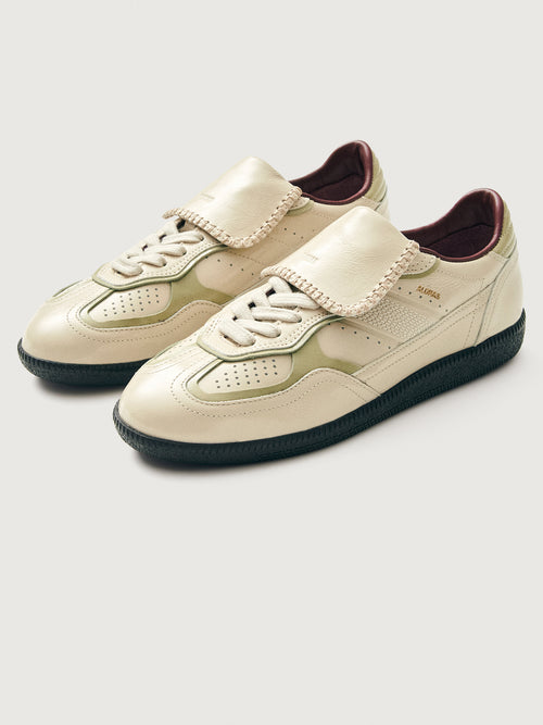 Creme colored low top lifestyle sneaker with black sole & gold/creme heel detailing. 