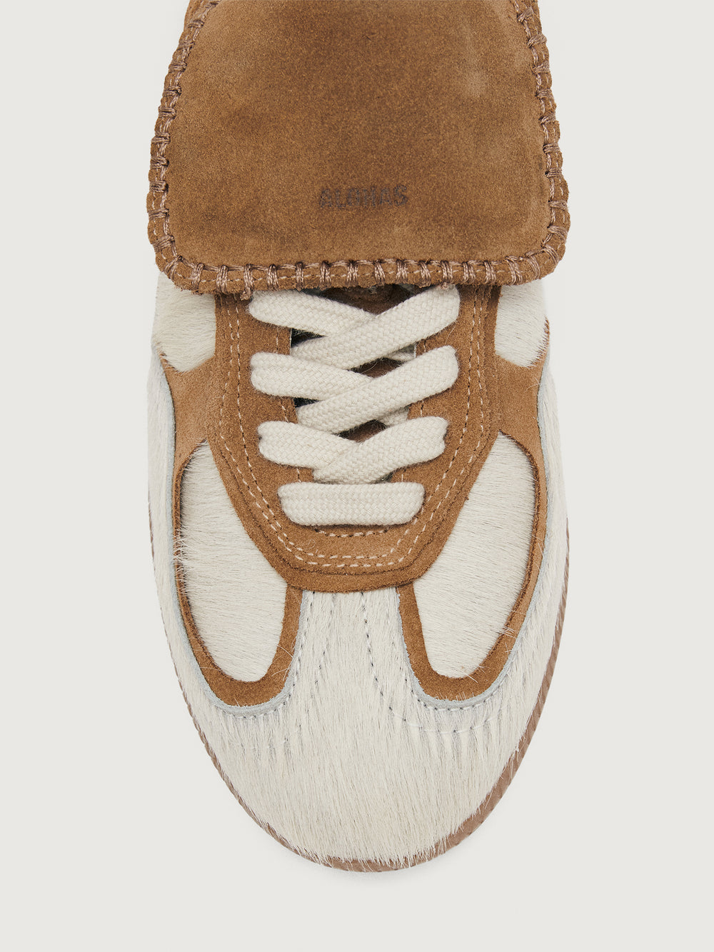 Neutral cowhair low top sneaker with chestnut tongue, sole, and heel. 