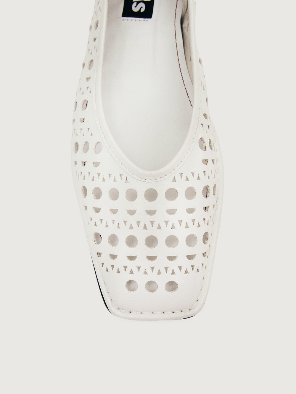 White flat shoe with cut-out design.