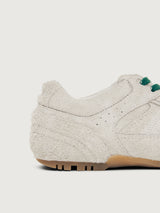 Grey sneaker with green and black laces.