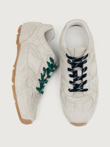 Grey sneaker with green and black laces.