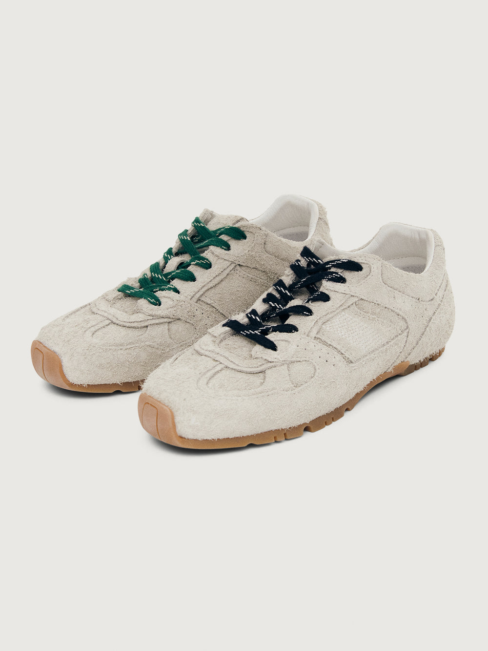 Grey sneaker with green and black laces.