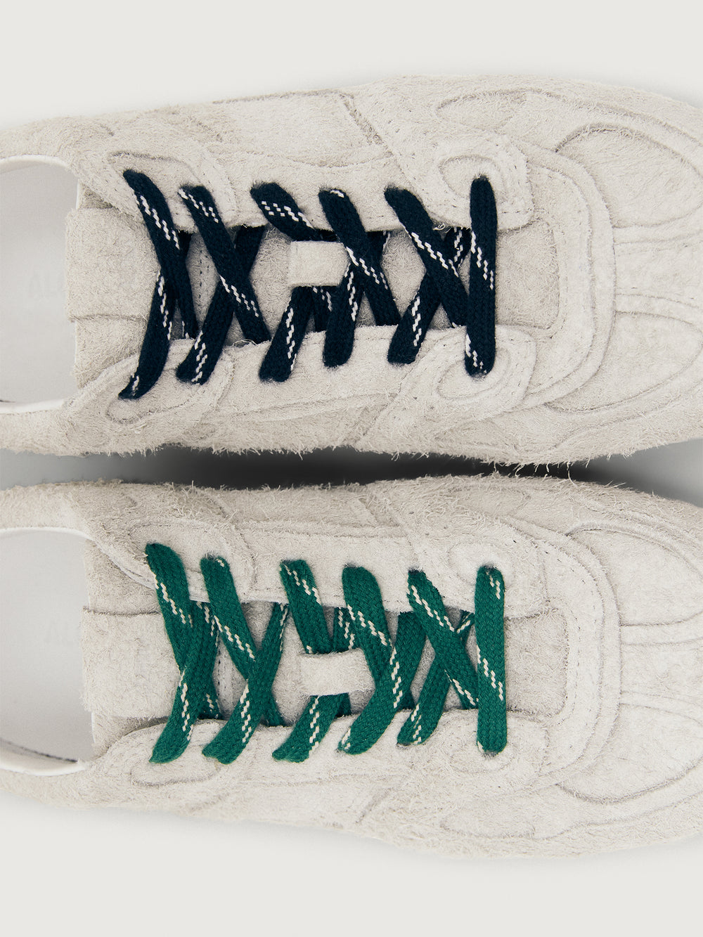Grey sneaker with green and black laces.