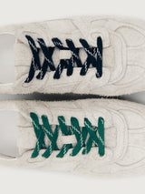 Grey sneaker with green and black laces.