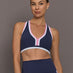 Model wearing Ida Top sports bra in navy with pink and white trim, front view.