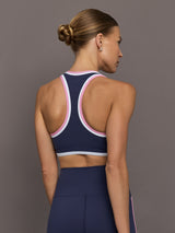 Back view of Ida Top sports bra in navy with racerback design and pink contrast trim.