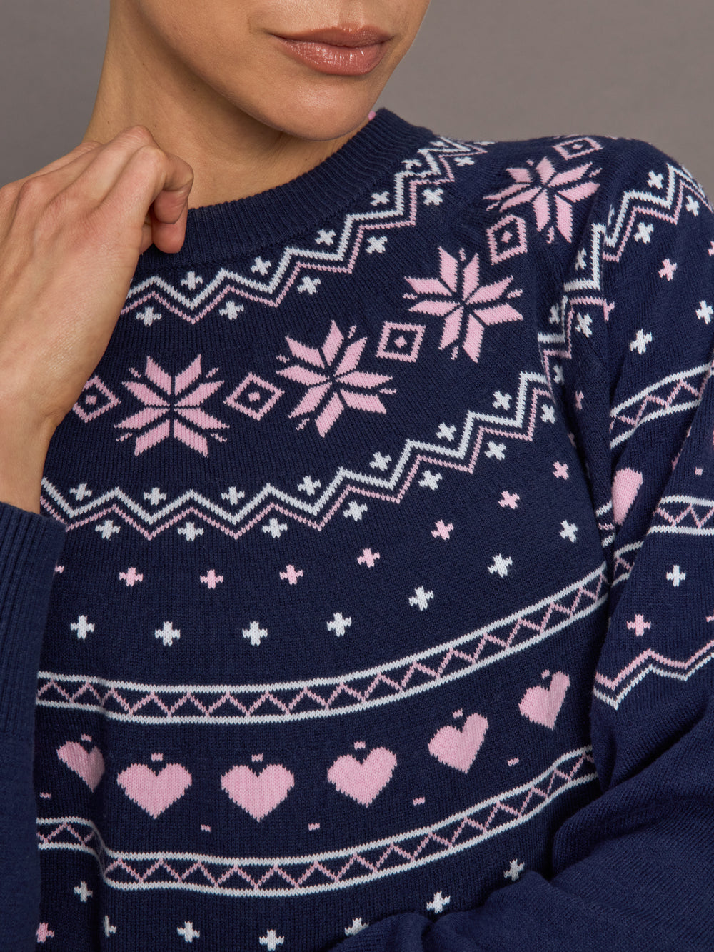 Close-up of Fair Isle sweater fabric showing pink hearts and snowflake motifs.