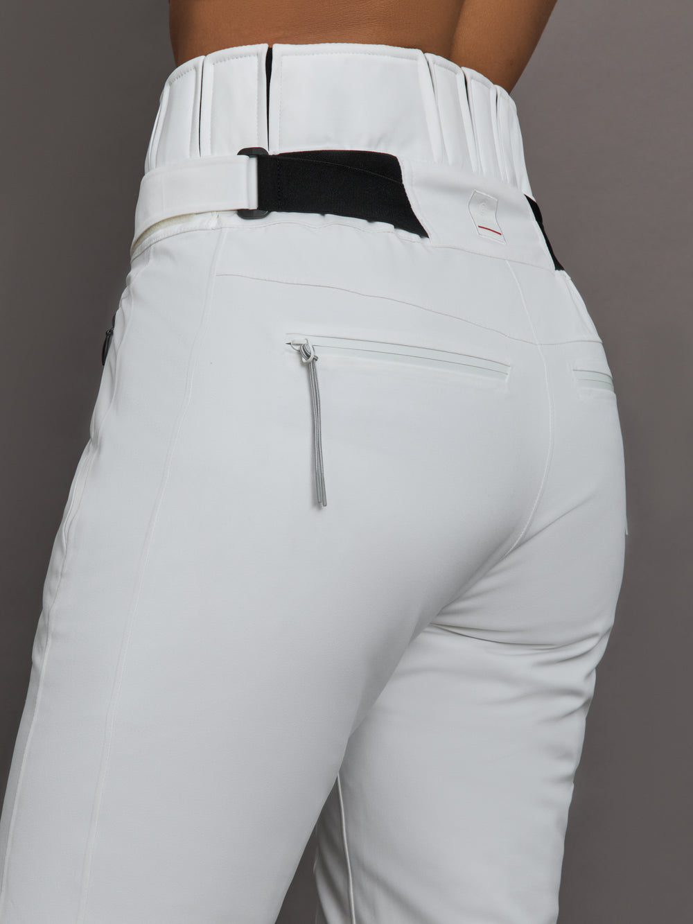 White ski pants with a black belt and zipper on a gray background