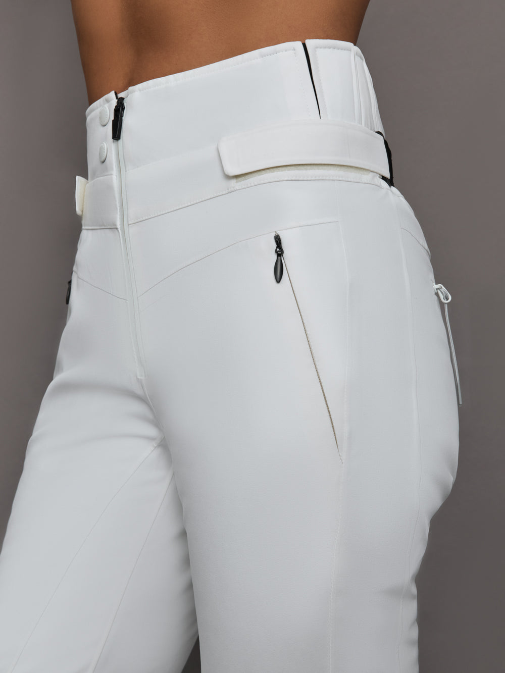 White pants with zippers and buttons on a gray background