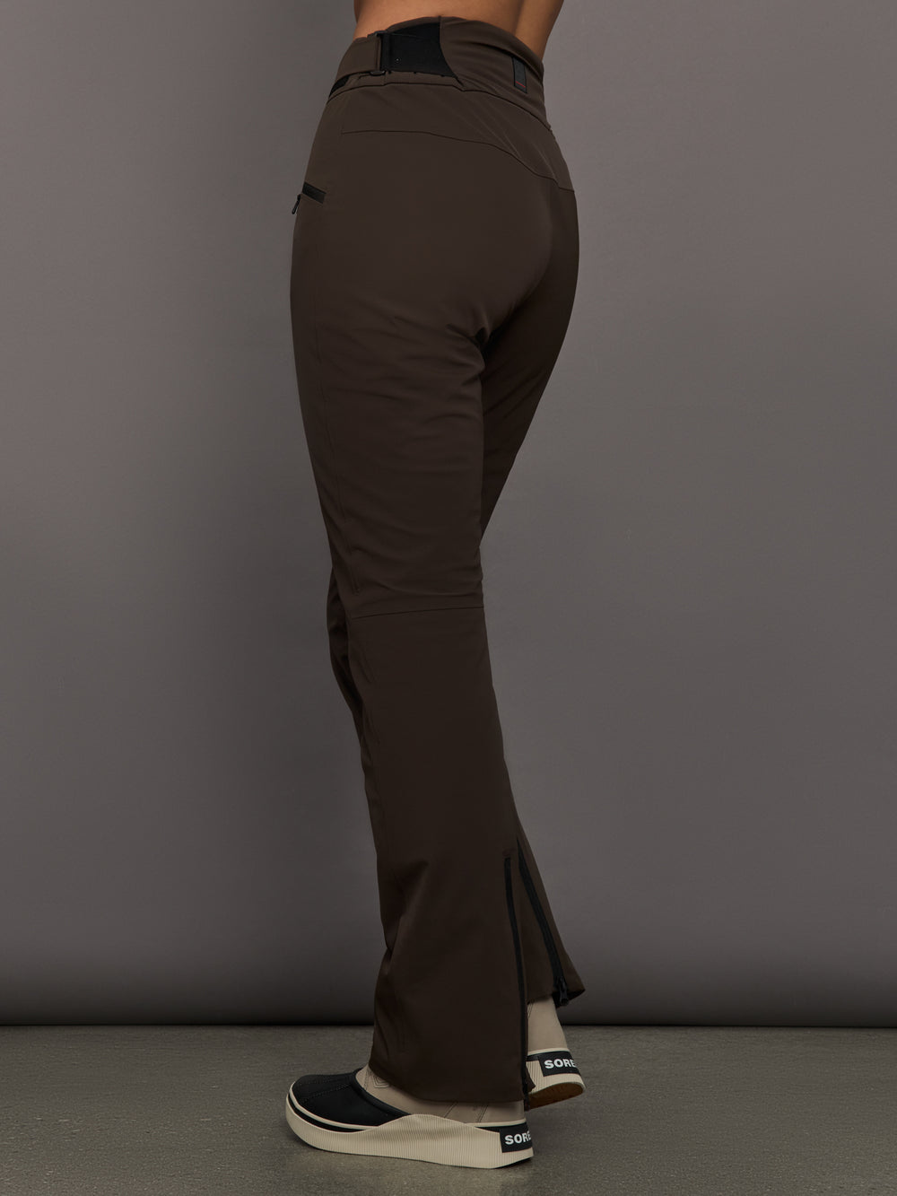 Brown ski pants worn by a person on a gray background