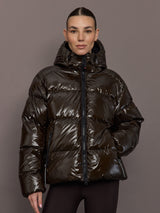 Woman wearing a shiny brown puffer jacket against a gray background