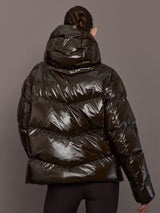 Woman wearing a shiny brown puffer jacket against a gray background