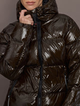 Woman wearing a shiny brown puffer jacket against a gray background