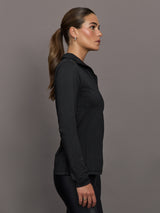 Woman wearing a black long-sleeve top against a gray background