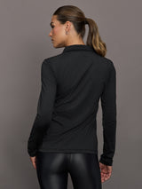 Person wearing a black long-sleeve athletic top and black leggings against a gray background
