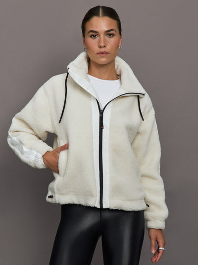 Woman wearing a white fleece jacket with black accents on a gray background