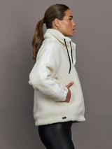 Woman wearing a white sherpa jacket against a gray background