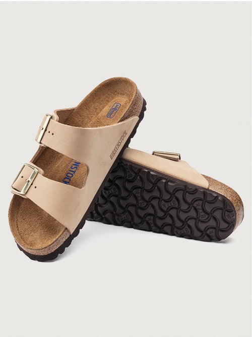 Beige Birkenstock Arizona Soft Footbed sandals with two adjustable straps and metal pin buckles on a cork sole.