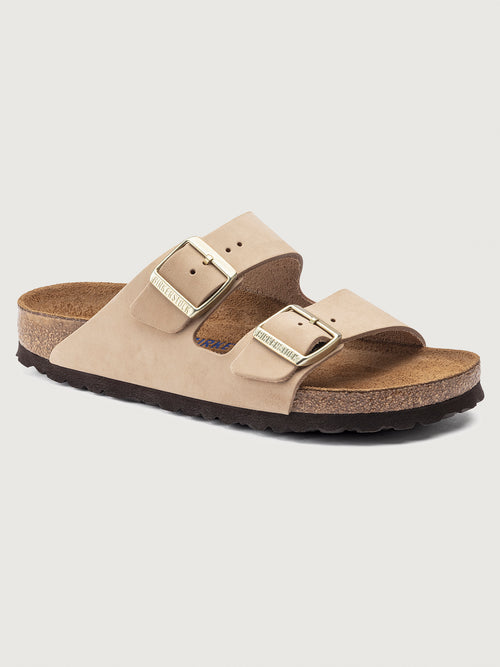 Beige Birkenstock Arizona Soft Footbed sandals with two adjustable straps and metal pin buckles on a cork sole.