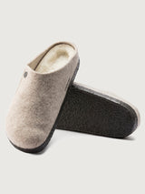 Pair of gray slippers with white interior on a light gray background