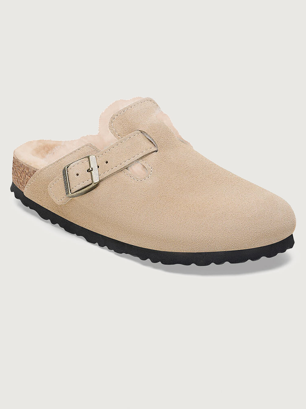 Beige suede clog shoe with a buckle on a light gray background