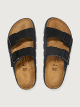 Pair of black sandals with brown soles on a light gray background