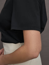 Model wears a basic black tee shirt with ringer neck and the word "Bandier" across the sleeve. 