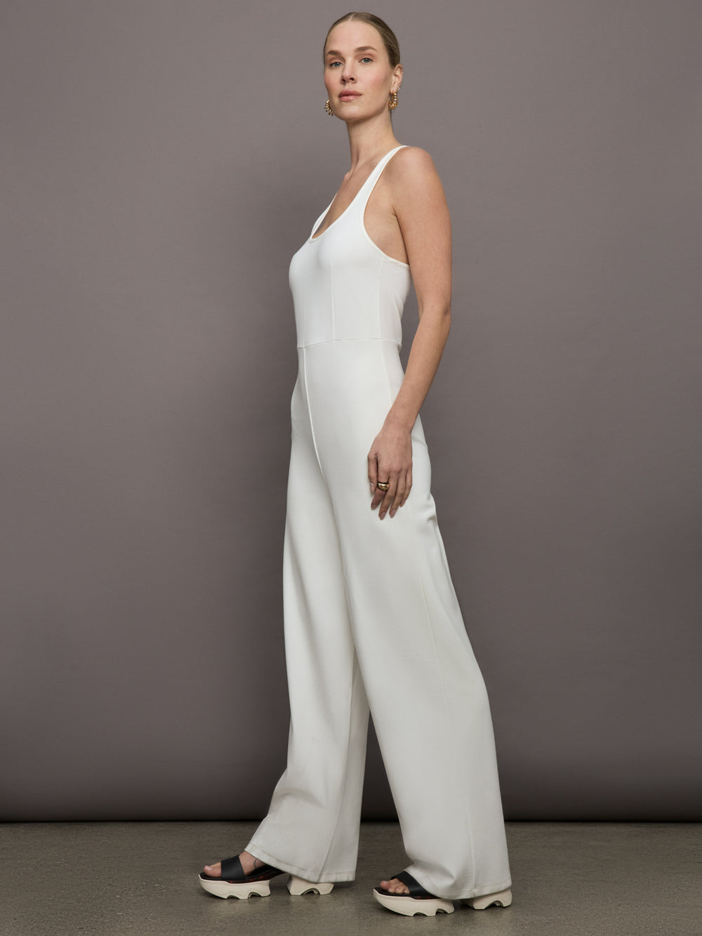 Model wears a white wide leg jumpsuit. 