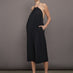 Model wears a loose fitting black dress with haltered neck that hits mid calf. 