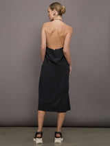 Model wears a loose fitting black dress with haltered neck that hits mid calf. 