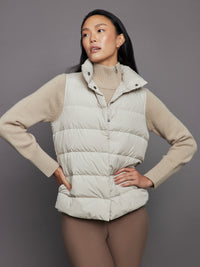 Woman in cream turtleneck sweater with puffer vest and leggings