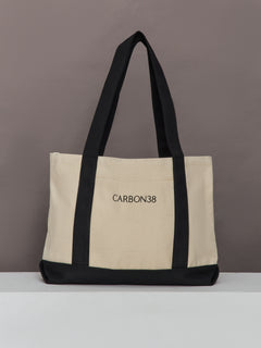 Carbon38 branded tote bag in ivory canvas with black straps and base, front view.