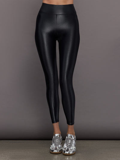 Model wears a mid rise waisted pair of liquidy shine black leggings that hit at model's mid to low calf.