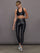 Model wears a mid rise waisted pair of liquidy shine black leggings that hit at model's mid to low calf.