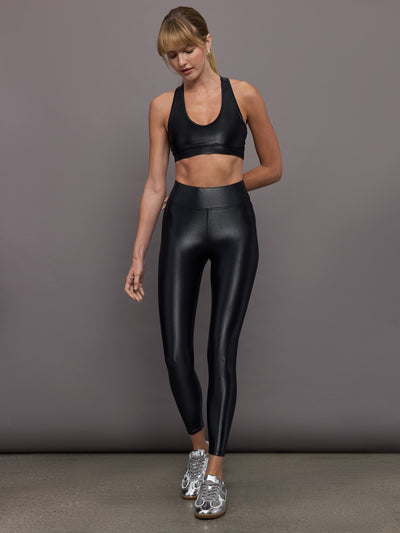 Model wears a mid rise waisted pair of liquidy shine black leggings that hit at model's mid to low calf.