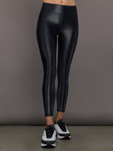 Model wears a mid rise waisted pair of liquidy shine black leggings that hit at model's mid to low calf.