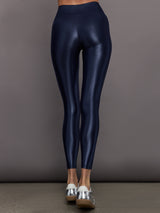 Model is wearing navy mid rise performance leggings in a liquidy-shine finish that hit above the ankle.